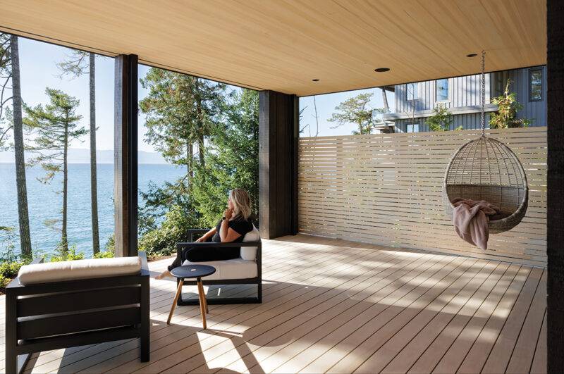 The private patio positioned off the primary ensuite is covered to allow for rainy days, the hanging chair an invitation to gaze at the ocean.